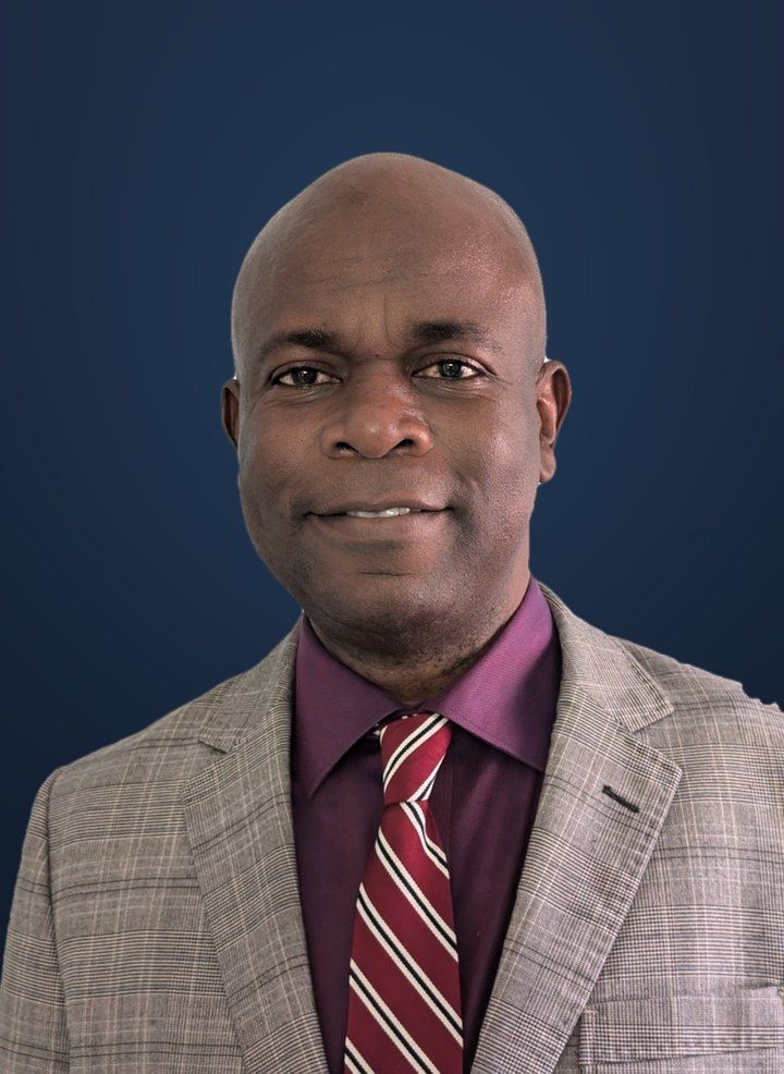 Raphael Adegboye in a grey suit and red tie